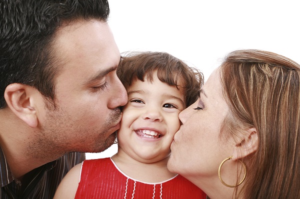 Parents giving their daughter a kiss.