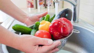 a-person-washing-vegetables-and-fruits-under-kitchen-water-faucet-16x9