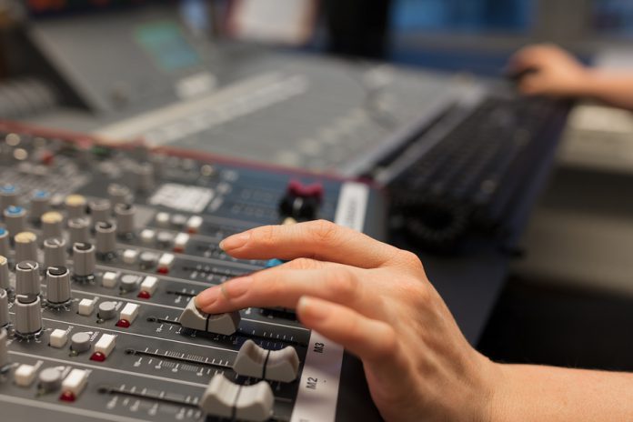 bigstock-Female-Radio-Host-Using-Adusti-238649665-696x464